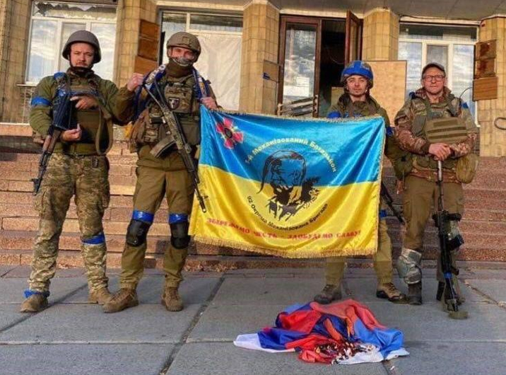 Ukrainian soldier proudly hold their flag with the Russian flag at their feet