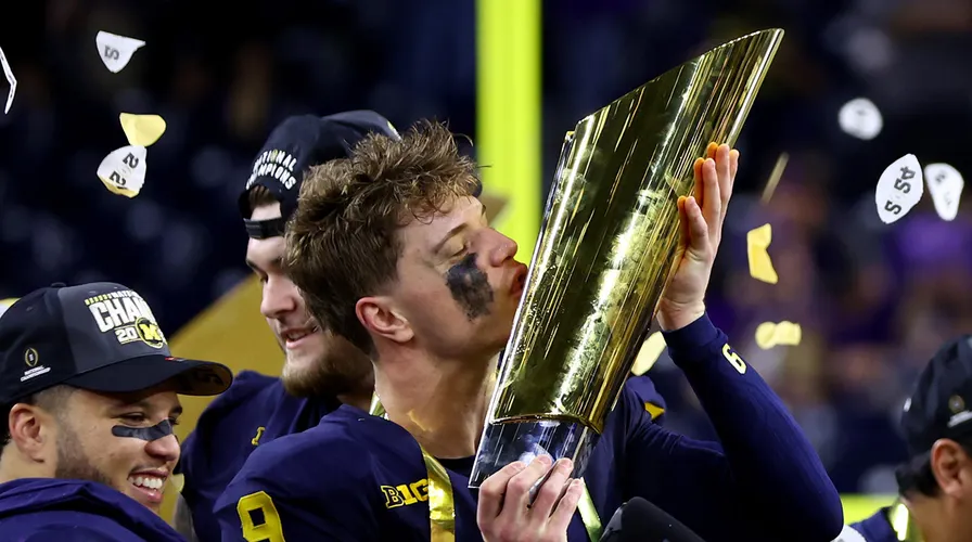 JJ McCarthy kissing the trophy after their win against Michigan.